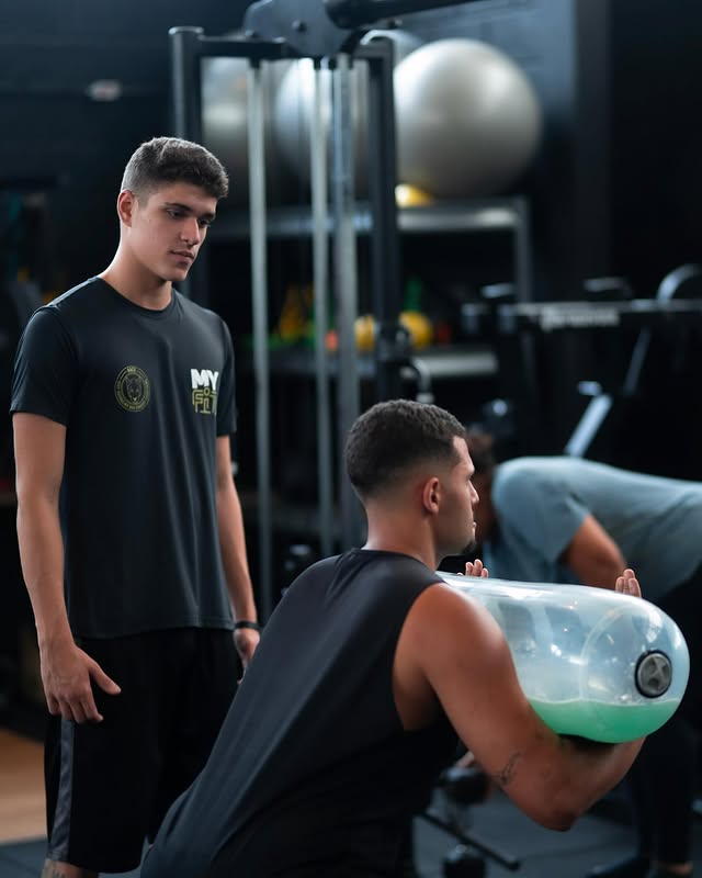Personal trainer ajudando cliente na academia